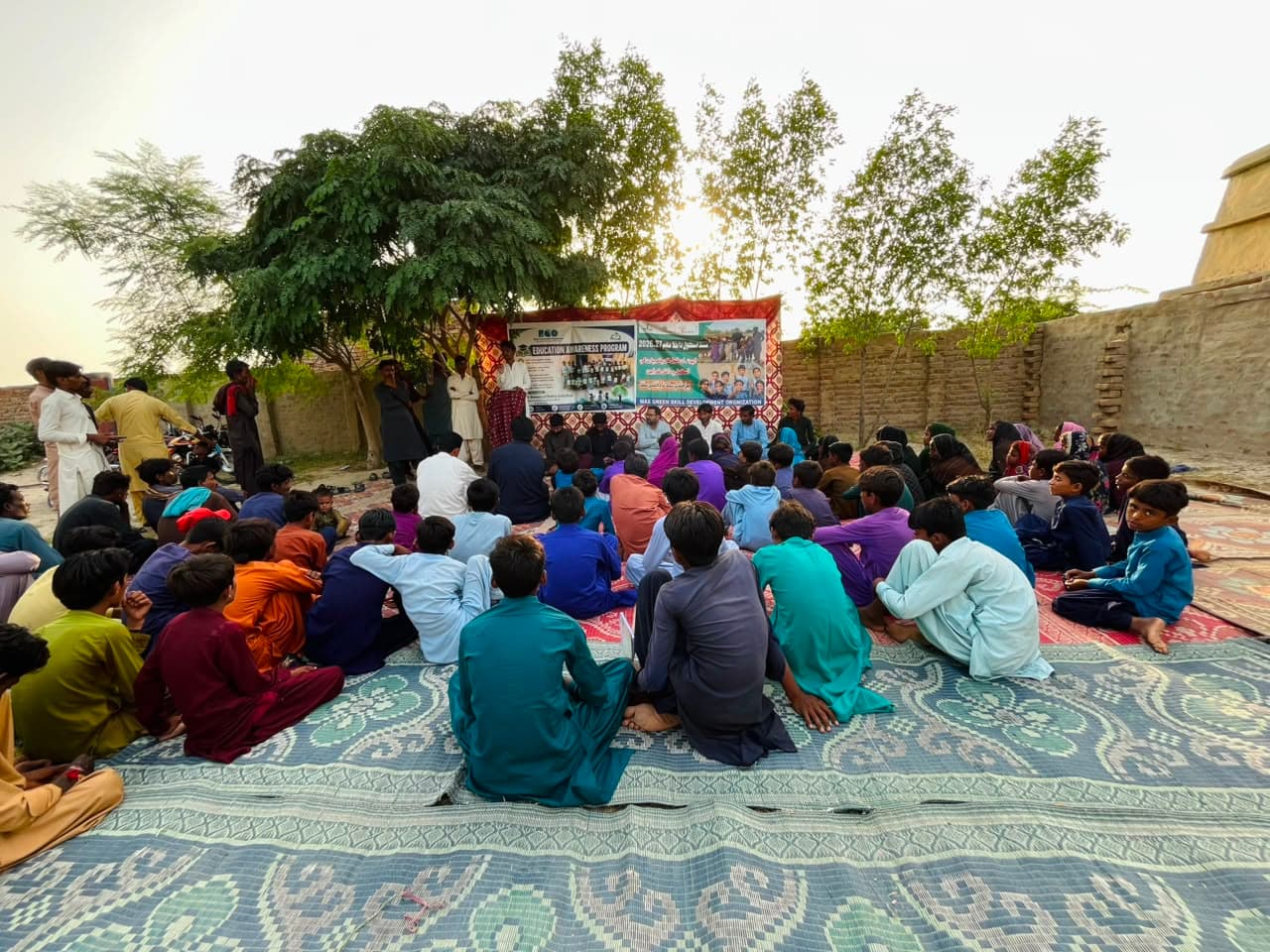 Students and families gathered under a tree for a BCO education awareness session